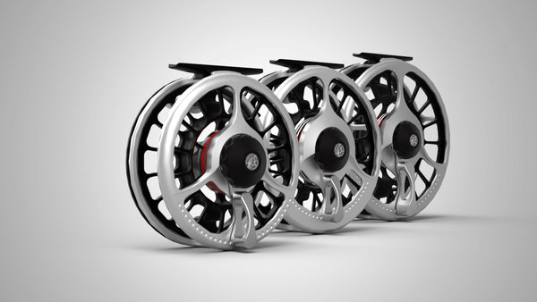 Set of three premium all aluminum saltwater fly reels featuring a silver machined frame, black ported spool, and red thrust plate accents, arranged in a clean studio setting.